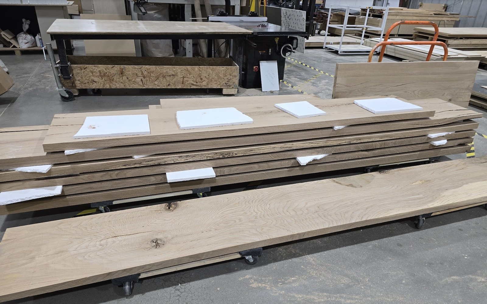 Stack of hardwood slabs on carts in the shop, ready for layout
