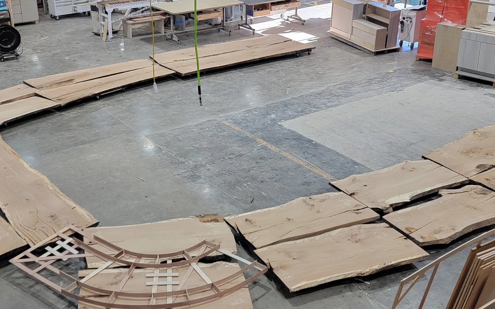 Live-edge slabs laid out on the shop floor in the shape of the bar, with a full-size template